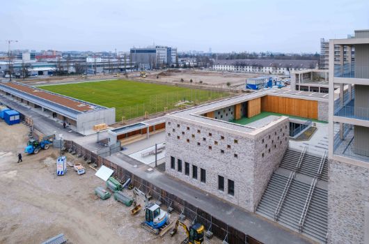 Blick aus dem  3. Obergeschoss des Gymnasiums auf die Grundschule und das Außensportgebäude mit Freisportflächen