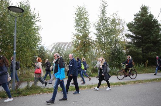 Teilnehmer der Planungszellen gehen im Freien an der Paketposthalle vorbei.