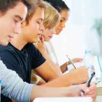 Mehrere Schüler in einer Reihe, die aufmerksam zuhören oder mitschreiben