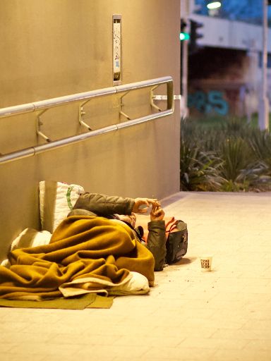 Mann schläft in seinem Schlafsack in einer Unterführung