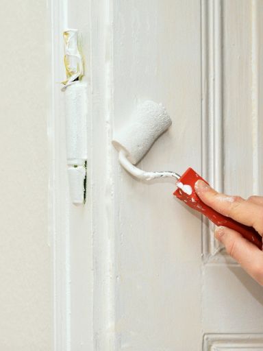 Eine alte Holztüre wird mit weißer Farbe neu angestrichen